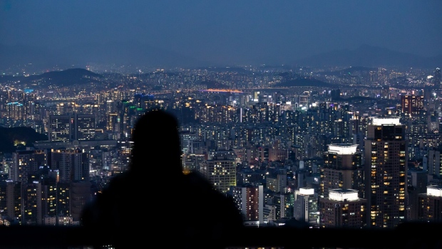 A woman is silhouetted as she looks at a city skyline from an observation deck of Woomyeon mountain at dusk in Seoul, South Korea, on Thursday, July 9, 2020. South Korea’s government is preparing new regulations to curb excessive house price gains that have fueled public discontent over inequality and property speculation.