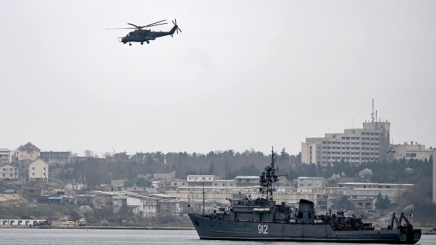 A Russian military helicopter flies over a Russian navy ship in the harbour at Sevastopol.