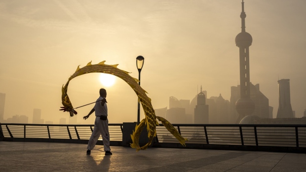 A pedestrian flies a dragon shaped kite along the bund in front of buildings in Pudong's Lujiazui Financial District in Shanghai, China, on Wednesday, June 21, 2023. China's yuan weakened past the closely watched 7.2-per-dollar level as investor sentiment soured on a lack of aggressive stimulus and Beijing signaled a level of comfort about the declines. Photographer: Raul Ariano/Bloomberg
