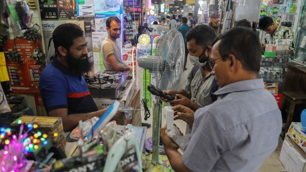 People browse battery and solar powered hand fans in Dhaka, Bangladesh, on Tuesday, Aug. 9, 2022. Bangladesh recently announced as much as 52% rise fuel oil prices, a record jump for the nation, sparking street protests. The power crisis was made worse after volatile global prices forced Bangladesh out of the spot market for liquefied natural gas cargoes. Photographer: ANIK RAHMAN/Bloomberg