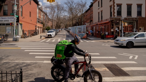 An Uber Eats delivery courier rides an electric bicycle through the Park Slope neighborhood of the Brooklyn borough of New York, U.S., on Friday, March 26, 2021. Dotted across hundreds of communities, roughly 13,000 bodega convenience stores have been a window into the state of mind and financial health of their local residents during the pandemic.