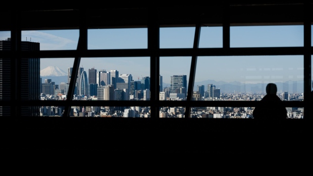 Mount Fuji stands beyond buildings as a visitor looks out at the skyline from an observation deck in Tokyo, Japan, on Friday, Jan. 11, 2019. Japan’s key inflation gauge slowed in the first back-to-back decline since April, highlighting the difficulty of the Bank of Japan’s price goal ahead of its policy meeting next week. Photographer: Akio Kon/Bloomberg
