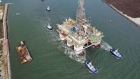 Tug boats tow a drilling platform through Texas’s Port Aransas Channel into the Gulf of Mexico.