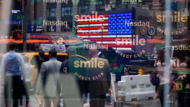 Monitors display SmileDirectClub Inc. signage as pedestrians are reflected in a window during the company's initial public offering (IPO) at the Nasdaq MarketSite in New York, U.S., on Thursday, Sept. 12, 2019. SmileDirectClub Inc. shares declined 12% from their initial public offering price in Thursday's debut.
