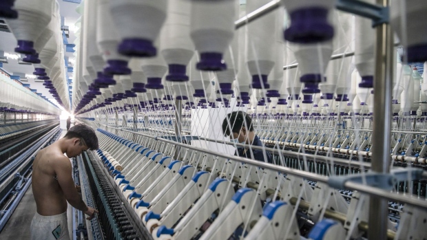 Workers stand in front of machines on a yarn production line at the Fujian Strait Textile Technology Co. factory in Putian, Fujian province, China, on Monday, Feb. 8, 2021. China may have got its control of Covid down to a handful of new cases per day, but the restrictions, quarantines and travel curbs to keep it that way have forced millions of factory workers to give up the idea of a traditional family gathering. Photographer: Qilai Shen/Bloomberg