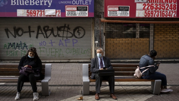 Pedestrians sit on benches outside of shuttered stores in Santiago, Chile, on Thursday, Sept. 2, 2021. Chile's central bank raised its 2021 growth and inflation forecasts as the economy runs hot, a day after policy makers delivered the biggest interest rate increase in two decades.