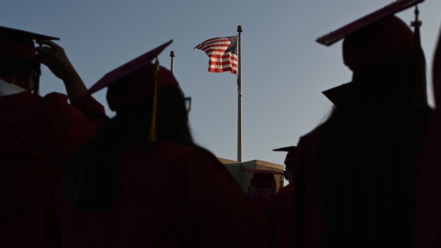 A US flag flies above a building as students earning degrees at Pasadena City College participate in the graduation ceremony, June 14, 2019, in Pasadena, California. Photographer: Robyn Beck/AFP/Getty Images
