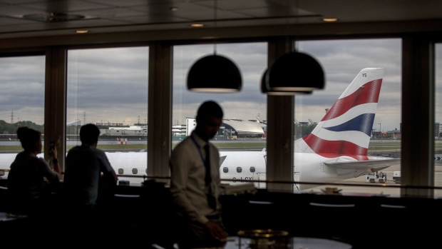 A passenger aircraft, operated by British Airways, a unit of International Consolidated Airlines Group SA (IAG), sits on the tarmac as travellers sit in a restaurant at London City Airport (LCY), in London, U.K., on Tuesday, Aug. 8, 2017. The chief Brexit concern of carriers is to maintain a single market for air travel which would allow existing routes between Britain and the EU to continue.