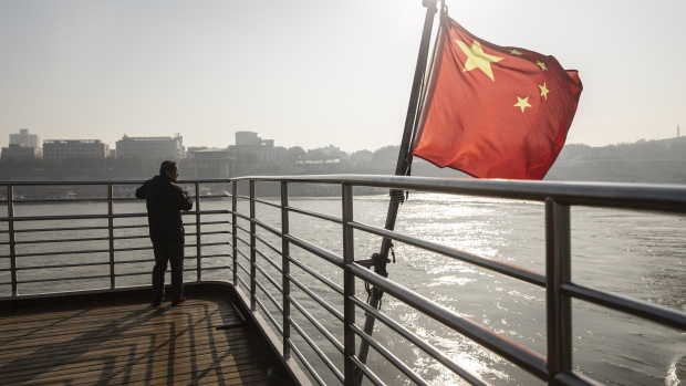 A Chinese national flag flies on the deck of a ferry crossing the Yangtze River in Wuhan, Hubei, China, on Wednesday, Dec. 11, 2019. China's economic growth will come in at 5.9% in 2020 as easing trade tensions and the prospect of lower bank borrowing costs boost confidence, according to analysts and traders. Photographer: Qilai Shen/Bloomberg