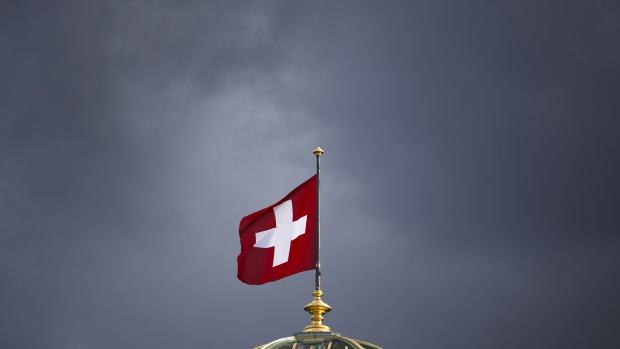 The Swiss national flag flies above the Federal Palace, Switzerland's parliament building in Bern, Switzerland, on Tuesday, March 12, 2013. The Swiss central bank pledged to keep up its defense of the franc cap after almost doubling its currency holdings to shield the country from the fallout caused by the euro zone's crisis. Photographer: Valentin Flauraud/Bloomberg