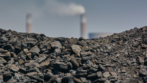 A pile of coal in front of industrial chimneys against a blue sky. Photographer: Bloomberg Creative Photos/Bloomberg Creative Collection