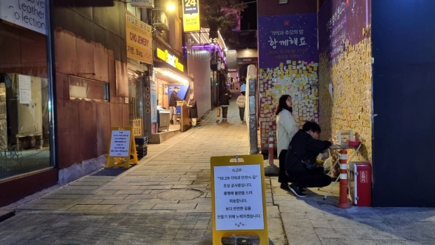 A couple reads messages on sticky notes on a wall at the alley of last year’s tragedy in Itaewon on Oct. 24.