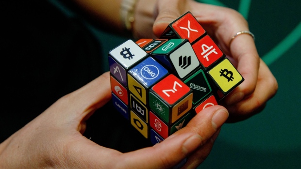 An attendee plays with a puzzle cube displaying logos of different cryptocurrencies and exchanges at the CryptoCompare Digital Asset Summit at Old Billingsgate in London, U.K., on Wednesday, March 30, 2022. Bitcoin and other cryptocurrencies had been, up until the last few weeks, mired in a similar downtrend as other riskier assets, like U.S. stocks. Photographer: Luke MacGregor/Bloomberg