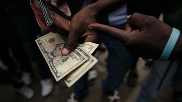Person holds US dollars. Photographer: JEKESAI NJIKIZANA/AFP