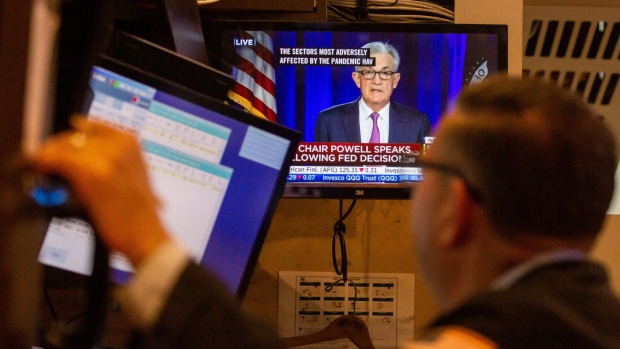 A trader works as a television broadcasts Jerome Powell speaks on the floor of the New York Stock Exchange.