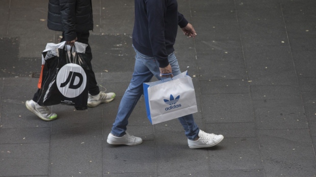 Shoppers carry a JD Sports, left, and Adidas shopping bag at Pitt Street Mall in Sydney, Australia, on Sunday, Sept. 3, 2023. Australia is scheduled to release its second-quarter gross domestic product (GDP) figures on Sept. 6. Photographer: Brent Lewin/Bloomberg