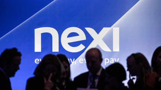 Attendees stand silhouetted against a Nexi SpA logo inside the Borsa Italiana, Italy's Stock Exchange, before the Nexi SpA launch ceremony in Milan, Italy, on Tuesday April 16, 2019. The initial public offering of payment-service company Nexi raised 2.01 billion euros ($2.3 billion), making it the biggest listing in Europe so far this year and the third major IPO of a payment-processing institution in the region in less than a year. Photographer: Alessia Pierdomenico/Bloomberg