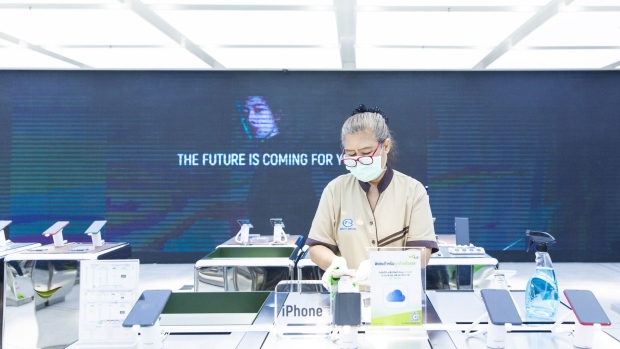 An employee wears a protective mask while disinfecting a smartphone on display an Advanced Info Service Pcl store in Central World Mall during a partial lockdown imposed due to the coronavirus in Bangkok, Thailand, on Monday, May 11, 2020. Thailand’s next stage of reopening the country would allow large businesses to resume operations if there’s no surge in new infections found, according to Taweesilp Witsanuyotin, a spokesman for the Covid-19 center on May 7.