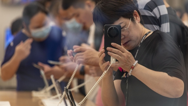 A visitor tries out a smartphone inside the Huawei flagship store on Nanjing East Road, one of the city's main commercial and tourist area, in Shanghai, China, on Saturday, Sept. 30, 2023. China's economy showed signs of a stronger recovery in September, according to a firm analyzing the global economy using satellite data. Photographer: Qilai Shen/Bloomberg   