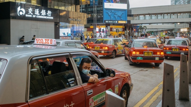 A driver looks out from a taxi while waiting for passengers in the Central district of Hong Kong, China, on Wednesday, Sept. 23, 2020. Hong Kong's economy has been rocked by anti-government protests in 2019 and the pandemic this year.