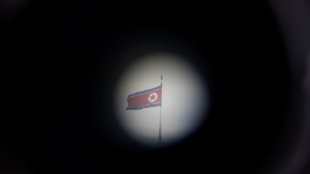 A North Korean flag flying over North Korea's Gijungdong village is seen through binoculars at the Daeseong-dong village in the Demilitarized Zone (DMZ) in Paju, South Korea. Photographer: SeongJoon Cho/Bloomberg