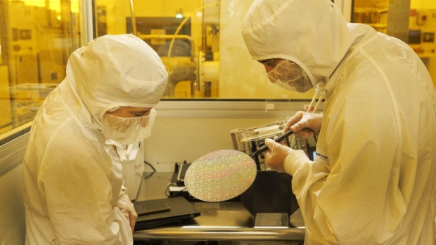 Technicians inspect a semiconductor wafer during testing.