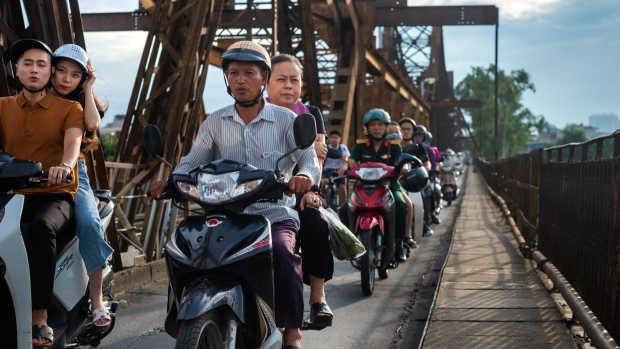 Motorcyclists travel along a road in Hanoi, Vietnam, on Friday, Sept. 18, 2020. Vietnamese billionaire Pham Nhat Vuong, the founder and chairman of Vingroup JSC, wants to help his nation’s 96 million motorbike riders go green, replacing their noisy gas guzzlers with electric scooters. Subsidiary VinFast has a new $3.5 billion, 36.1 million-square-foot factory in Haiphong, where it’s building e-scooters, electric buses, and electric cars. Photographer: Linh Pham/Bloomberg