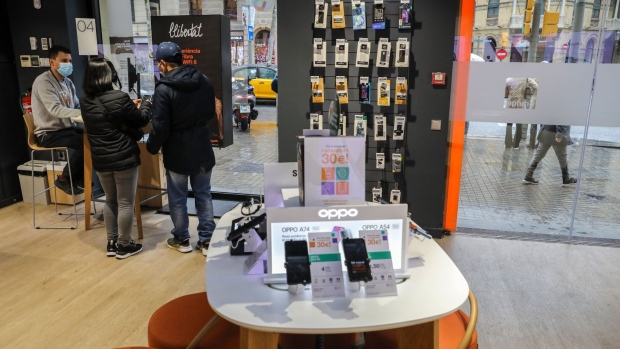 A retail assistant assists customers inside an Orange SA store in Barcelona, Spain, on Tuesday, March 8, 2022. Orange and Masmovil Ibercom SA have entered exclusive merger talks in an attempt to consolidate the Spanish telecom market, in a deal that would give the combined company a total enterprise valuation of 19.6 billion euros ($21.3 billion).