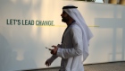 An attendee passes a sign reading 'Let's Lead Change' in the Blue Zone on day two of the COP28 climate conference at Expo City in Dubai, United Arab Emirates, on Friday, Dec. 1, 2023. More than 70,000 politicians, diplomats, campaigners, financiers and business leaders will fly to Dubai to talk about arresting the world’s slide toward environmental catastrophe. Photographer: Annie Sakkab/Bloomberg