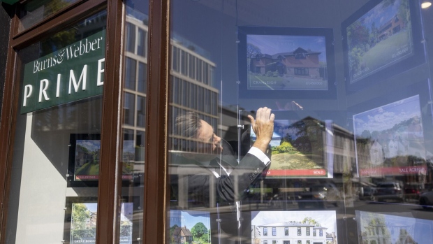 An employee removes an advertisement for a sold property from the window of an estate agent in Guildford, UK, on Monday, Sept. 4, 2023. The downturn gripping the UK housing market steepened in August as the cost-of-borrowing squeeze sapped demand, according to a major mortgage lender. Photographer: Jason Alden/Bloomberg