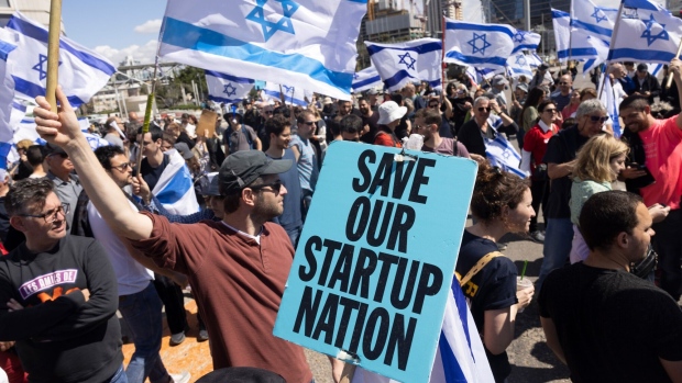 A demonstrator holds a placard reading "Save Our Startup Nation" during a protest, by tech workers against proposed judicial reforms, in Tel Aviv, Israel, on Thursday, March 9, 2023. Tens of thousands headed for protests across Israel over the government’s plan to cut the power of the Supreme Court, while the US defense secretary will shorten his visit and the chief of the army expressed alarm over a threat from reservists to withhold service.