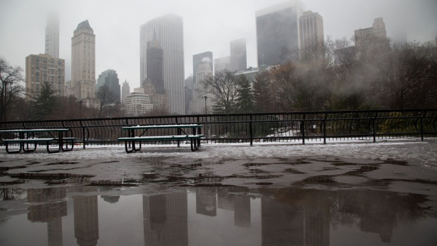 The skyline is reflected in a puddle of melted slow in Central Park following a storm in New York, US, on Tuesday, Feb. 28, 2023. New York City and the Northeast had a slushy start Tuesday as a storm brought the first significant snowfall of the season to the region, grounding hundreds of flights.