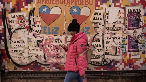 A pedestrian in front of a wall covered with posters of approval and rejection of the new Constitution in Santiago, Chile