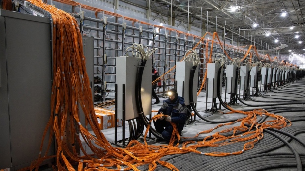A technician installs ethernet and power cables for mining rigs at a cryptocurrency mining center.