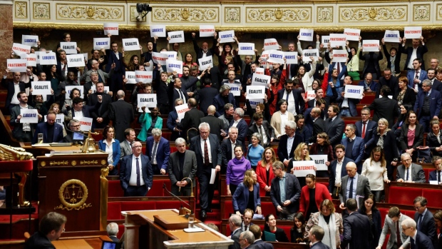 Left-wing coalition NUPES members of parliament hold signs reading "Liberte", "Egalite", "fraternite" French for 'liberty, equality, fraternity', the national motto of France, following the vote and the approval of the draft law to control immigration, at the French National Assembly in Paris on December 19, 2023. Photographer: Ludovic Marin/AFP/Getty Images