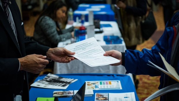 A job seeker hands a resume to a representative during a career fair in New York.