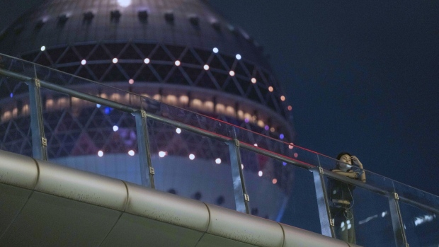 A pedestrian on a footbridge in front of the Oriental Pearl Tower in Pudong's Lujiazui Financial District at night in Shanghai, China, on Monday, Sept. 18, 2023. China's central bank will strengthen efforts to stabilize trade and improve the business environment for foreign firms, its governor said Monday, adding to pledges among top leaders this year to open up to overseas investors. Photographer: Raul Ariano/Bloomberg
