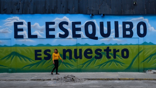 A pedestrian walks past a mural that reads “The Essequibo Is Ours,” during a referendum vote in Caracas, Venezuela, on Sunday, Dec. 3, 2023.