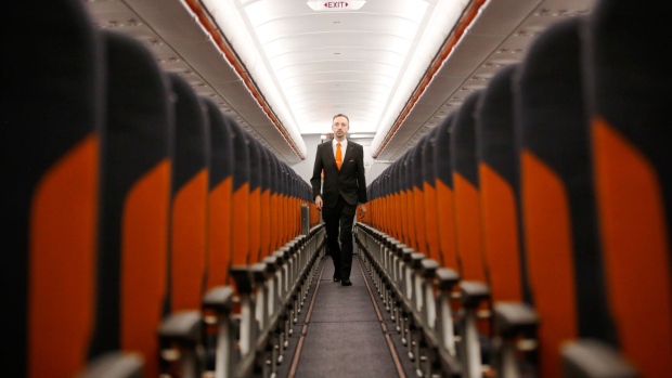 A member of EasyJet Plc cabin crew walks along the aisle of an Airbus SE A320 Neo passenger aircraft during the airlines annual innovation day at London Gatwick airport in Crawley, U.K., on Wednesday, Sept. 27, 2017. EasyJet revealed that it's working with U.S. startup Wright Electric to develop a battery-powered plane. Photographer: Luke MacGregor/Bloomberg