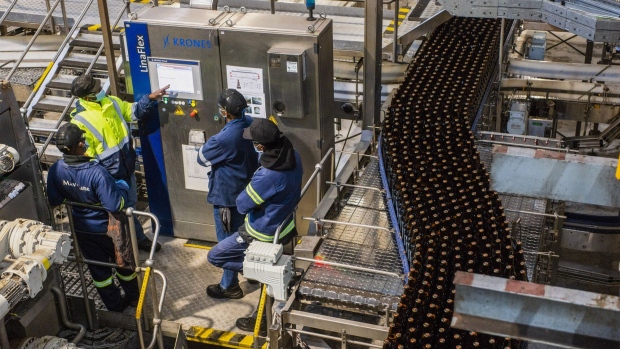 Workers stand and speak by the bottling line control unit at the SABMiller Plc Alrode brewery and bottling plant, a unit of Anheuser-Busch InBev SA, in Johannesburg, South Africa, on Tuesday, Aug. 11, 2020. South Africa’s ban on alcohol sales has put investment projects worth at least 12.8 billion rand ($742 million) on hold.