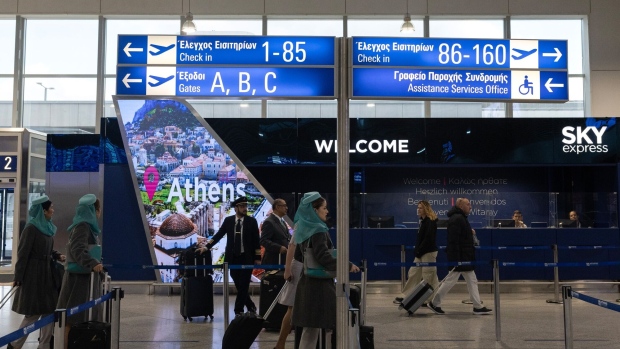 Passengers and airline crew walk through Athens International Airport SA in Athens, Greece. Photographer: Yorgos Karahalis/Bloomberg