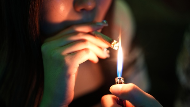 A customer lights up a joint inside a cannabis dispensary in Bangkok. Photographer: Dimas Ardian/Bloomberg