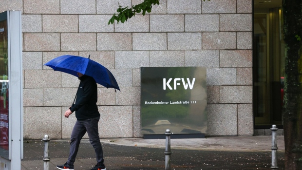 A pedestrian shelters under an umbrella outside the KfW state-owned bank headquarters in Frankfurt, Germany, on Wednesday, May 26, 2021. Europe’s labor market may recover more slowly from the pandemic than its economy, according to a study by Accenture.