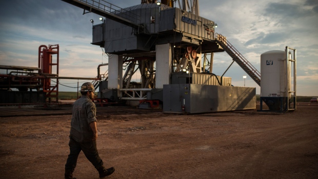 A worker walks past rigging on an oil drilling site on the Bakken shale formation outside Watford City, North Dakota. 