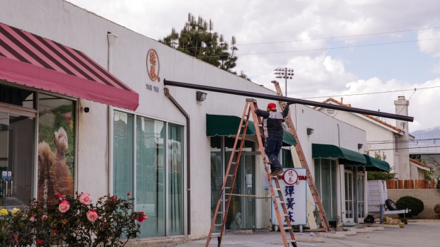 A construction worker stands on a ladder outside a store at a strip mall in San Gabriel, California, U.S., on Tuesday, March 23, 2021. The U.S. economy is on a multi-speed track as minorities in some cities find themselves left behind by the overall boom in hiring, according to a Bloomberg analysis of about a dozen metro areas. Photographer: Jessica Pons/Bloomberg