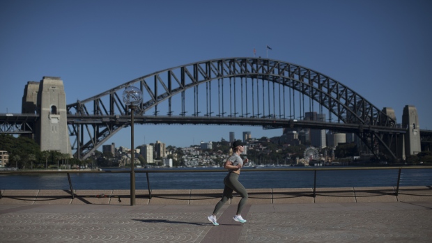 A woman runs past the Sydney Harbour Bridge in Sydney, Australia, on Sunday, Dec. 3, 2023. Australia will release its third-quarter gross domestic product (GDP) figures on Dec. 6. Photographer: Brent Lewin/Bloomberg