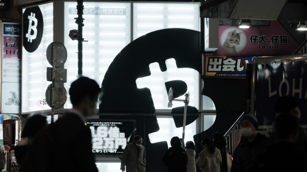 Pedestrians walk past a Sakura Bitcoin Exchange Inc. store in the Shibuya district of Tokyo on Friday, Feb. 25, 2022. Cryptocurrency exchanges are still trying to figure out how to deal with western sanctions against Russia after its invasion of Ukraine. Photographer: Soichiro Koriyama/Bloomberg