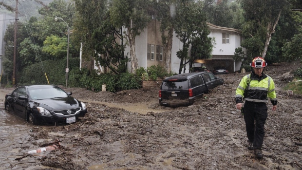 A firefighter walks on mud and rocks from a mudslide during a storm in Los Angeles, California, US, on Monday, Feb. 5, 2024. Heavy rains inundated California, raising the risk of life-threatening floods and leaving hundreds of thousands of people without power as a powerful Pacific storm batters the state.