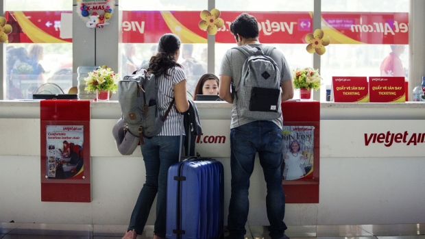 Travelers stand at a Vietjet Aviation JSC ticket counter at the Tan Son Nhat International Airport in Ho Chi Minh City, Vietnam, on Saturday, Dec. 22, 2018. Vietnam's Civil Aviation Authority estimates that the nation's airports handled 106 million passengers in 2018, a 12.9 percent increase year on year, according to a statement released on Dec. 12. Photographer: Maika Elan/Bloomberg