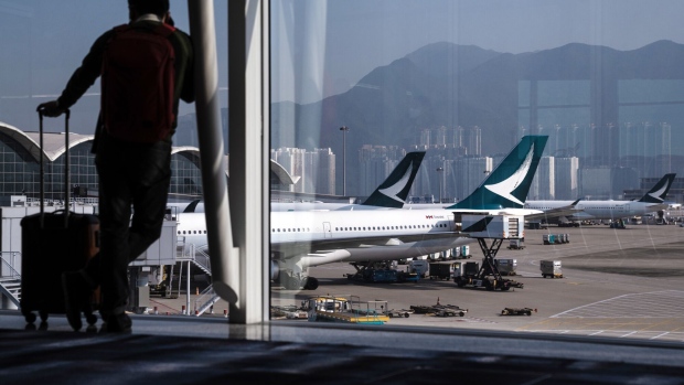 A traveler in front of Cathay Pacific Airways Ltd. aircraft at Hong Kong International Airport in Hong Kong, China, on Friday, Feb. 17, 2023. A scarcity of workers in the air industry is hobbling Hong Kong's efforts to reestablish the international links vital for its role as a financial hub. Photographer: Lam Yik/Bloomberg